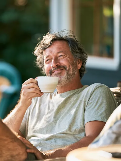 Man in his 50s sipping tea on his front porch after reviewing medical bill options with a Hidden Meadow Lending guide