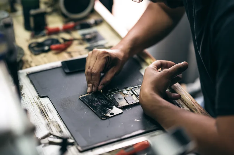 Technician replacing a cracked smartphone screen at a repair bench, a common reason to request a $500 loan