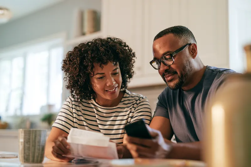 Couple in their 40s calmly reviewing household bills together at a kitchen table